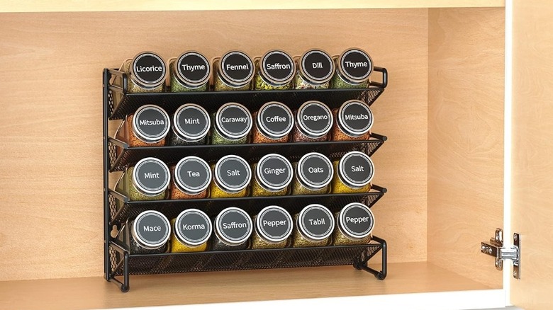 A black spice organizer loaded with jars in a cabinet