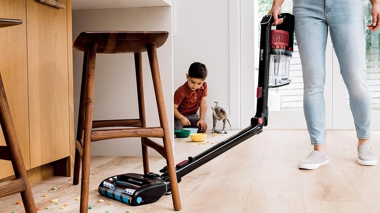 Woman vacuuming under furniture with a Shark vacuum