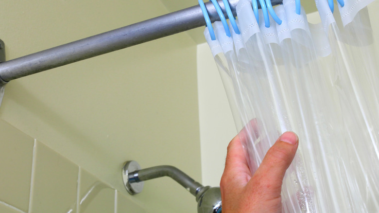 A man pulls on a clear shower curtain liner