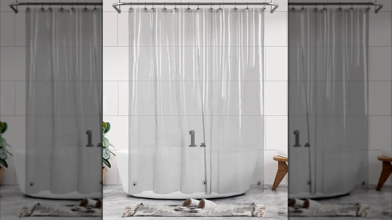 Clear plastic shower curtain hanging around a freestanding bathtub.
