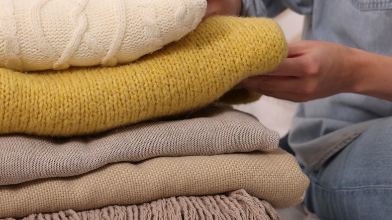 Person going through a stack of different folded blankets