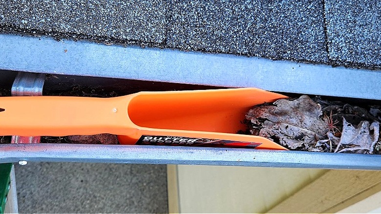 A shot showing Vivid Works' Gutter Scoop inside a leaf-strewn gutter