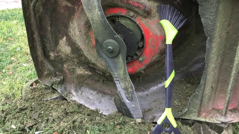 The Walensee lawn mower scraper brush sitting next to the underside of a mower deck