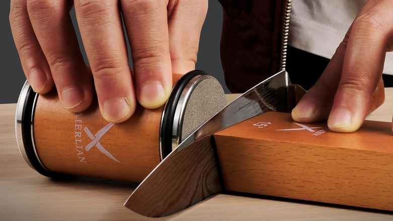 a person using a AIERLIAN rolling knife sharpener to sharpen a knife