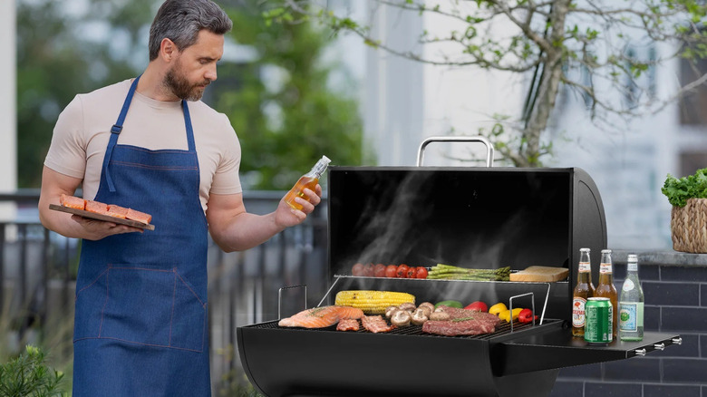 A person wearing a blue apron cooking with a Royal Gourmet grill