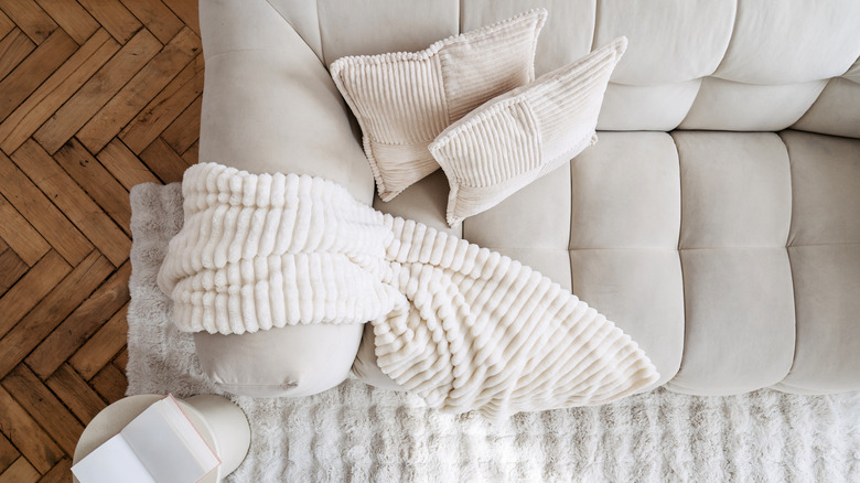 Top view of stylish modern room interior showcases a comfortable white couch adorned with soft pillows and a cozy blanket