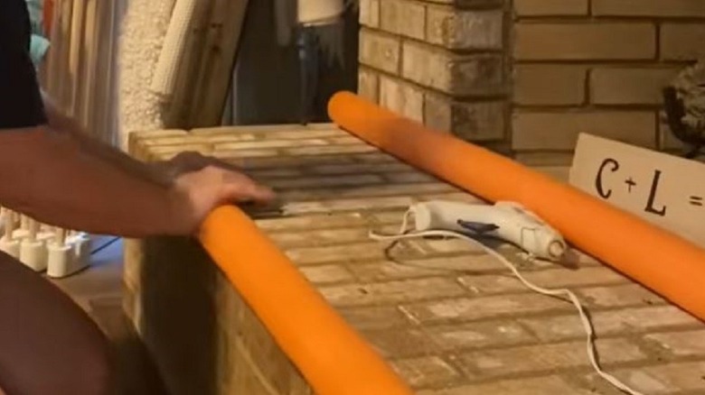 Woman making fireplace safer with pool noodles