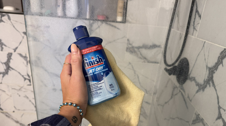Rinse Aid and microfiber cloth in front of shower glass