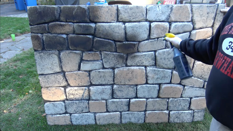 Spraying a DIY rock wall with black paint