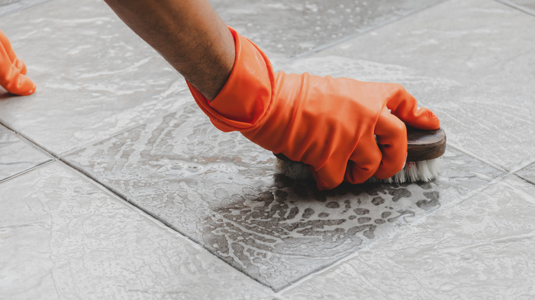 Gloved hand scrubbing soapy floor