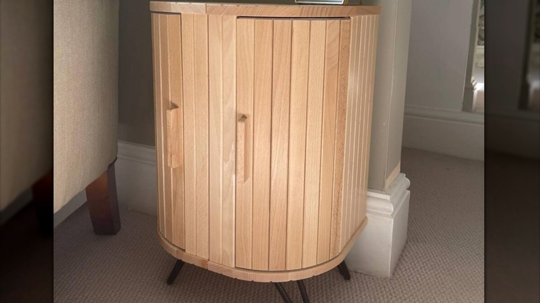 Wooden table made from bread bins standing against beige wall.