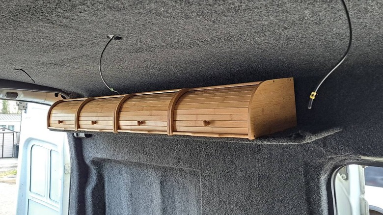 Interior of a Ford Transit van a set of IKEA bread bins along the side of the ceiling mounted for storage