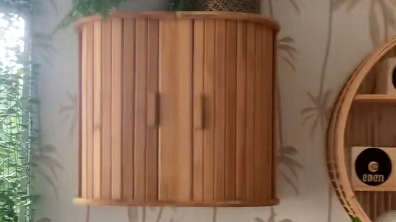 Wall mounted cabinet made from two bread bins next to a rattan hanging circle in a bathroom