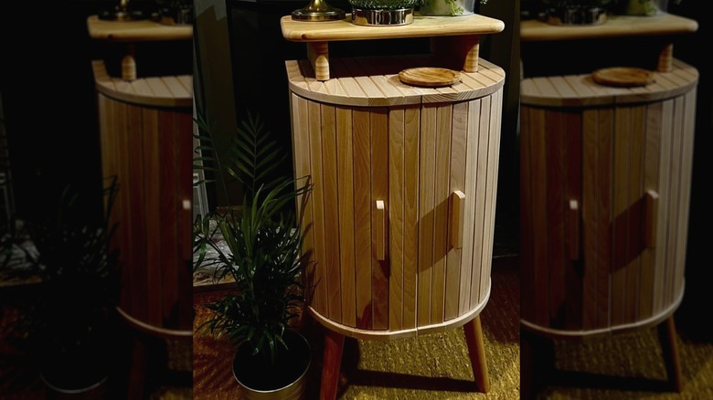 Two tiered side table made with bread bin and cutting board from IKEA in a room next to a plant