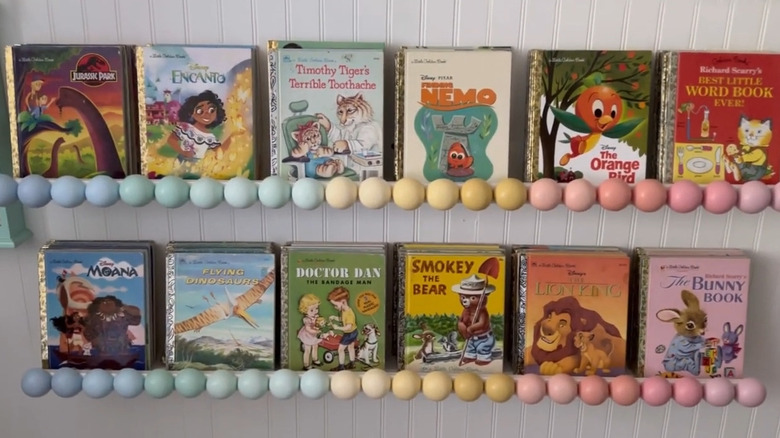 Rows of Little Golden Books hung on a MOSSLANDA shelf featuring pastel bobbin decorations