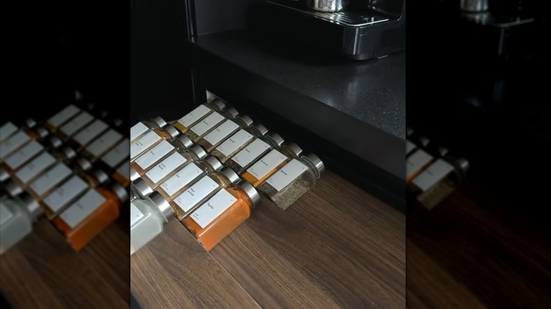 view of a spice drawer with spices on picture ledges flipped upside down to create a riser
