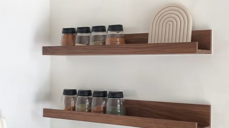 Dark wood picture ledge used as spice rack on wall