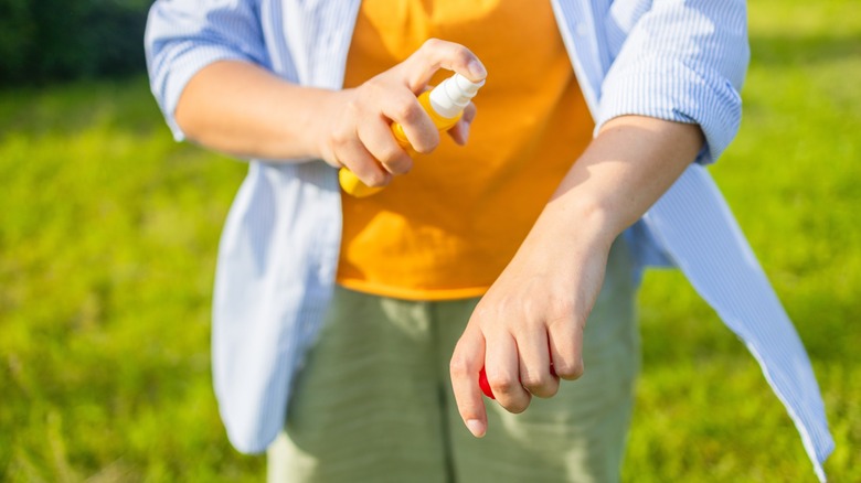 Person using insect repellent spray outdoors