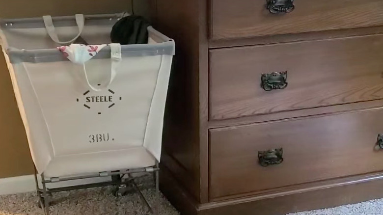 vintage rolling canvas laundry cart next to dresser