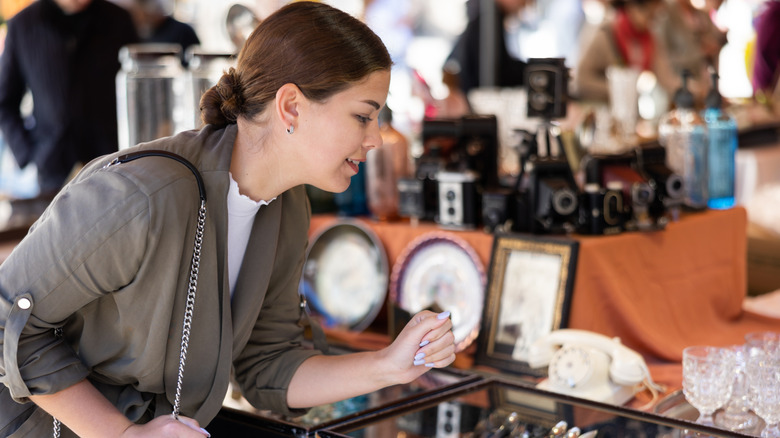 Woman eyes cutlery and cups in antique store