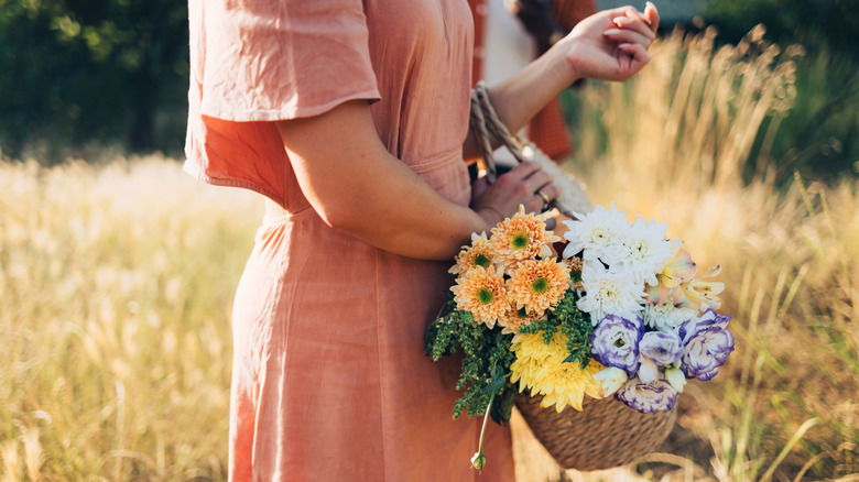 A woman carrying a wicker basket full of flowers