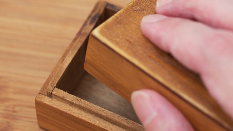 A person opening small wooden box.