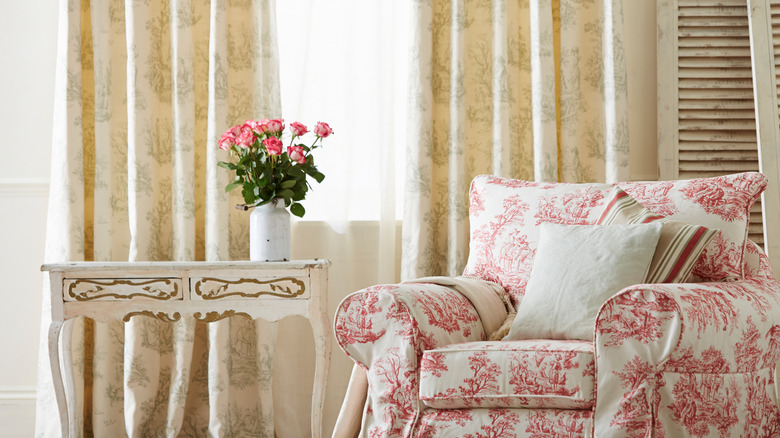 Skirted chair with a red print next to a vintage table