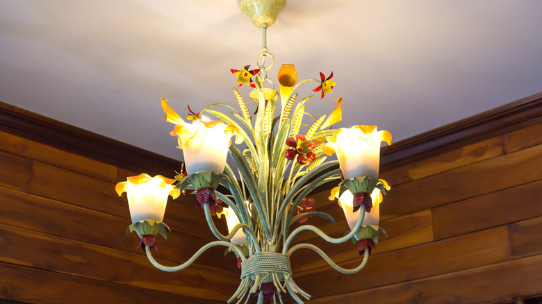 A tole chandelier with flowers and leaves.