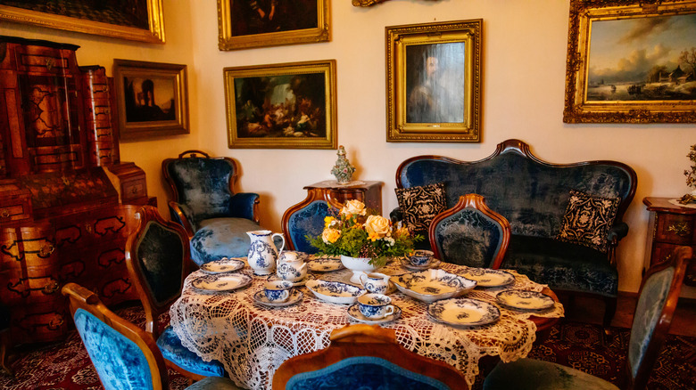 A formal dining room with ornate gold-framed paintings