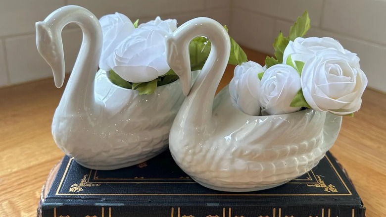 Two white swan vases on an old book