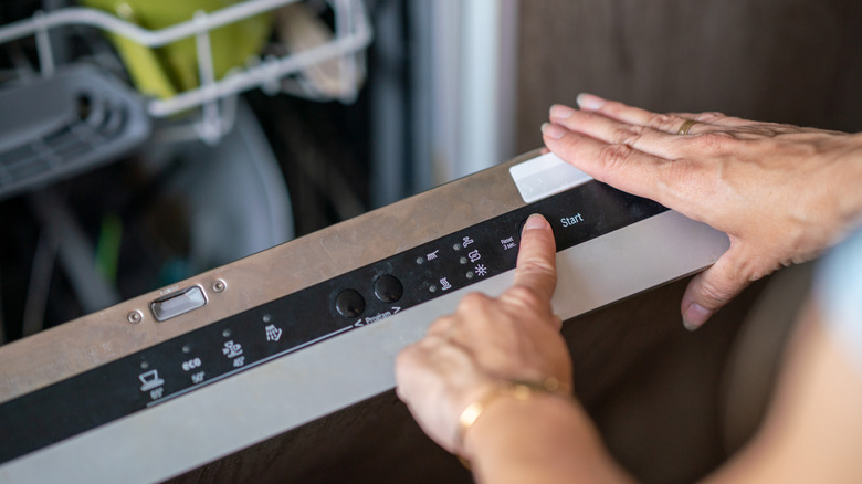 Close-up of a person's hands selecting a dishwashing cycle