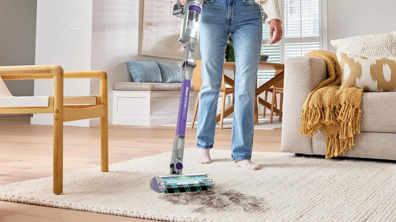 Woman using the Shark PowerDetect vacuum on an area rug