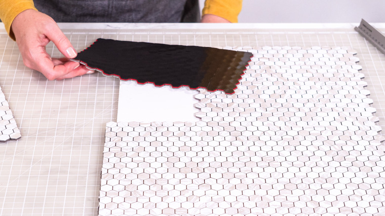A hand holding a peel-and-stick tile section
