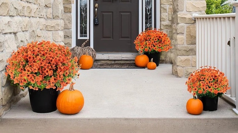 Three planters with artificial mums displayed on someone's front porch