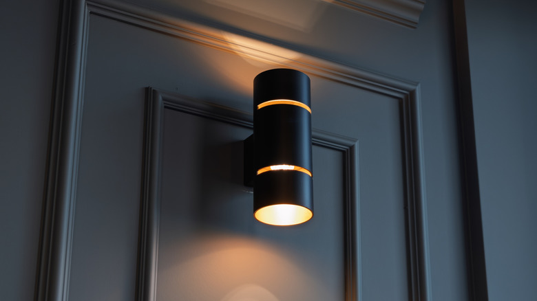 Close-up of a black battery-powered wall light softly illuminating a paneled wall