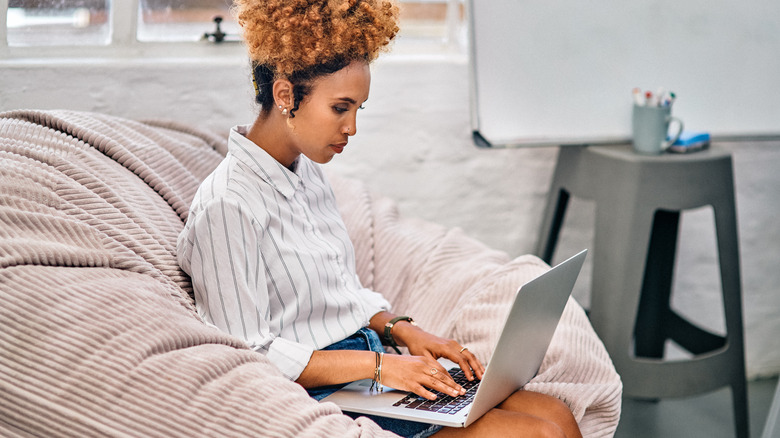 Woman with laptop on bean bag chair 