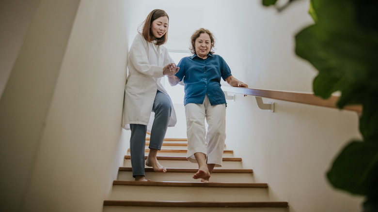 A person helping elderly down staircase