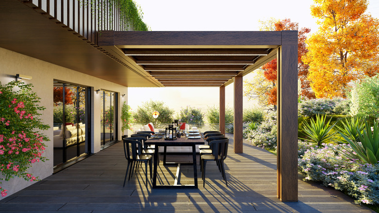 A bright patio with dark wood floors and a set dining table