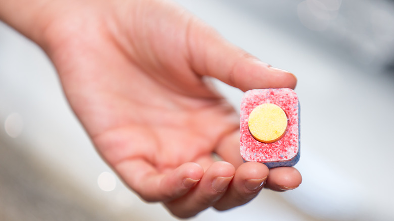 Hand holding dishwasher tablet