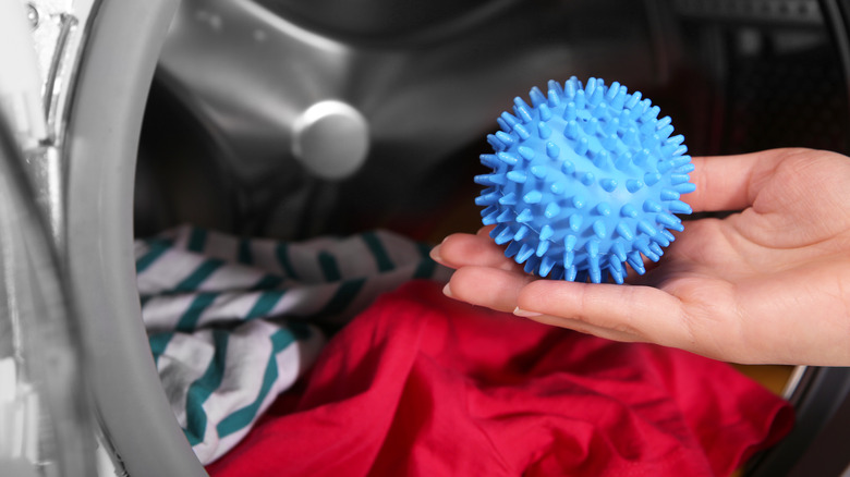 Hand adding dryer ball to machine