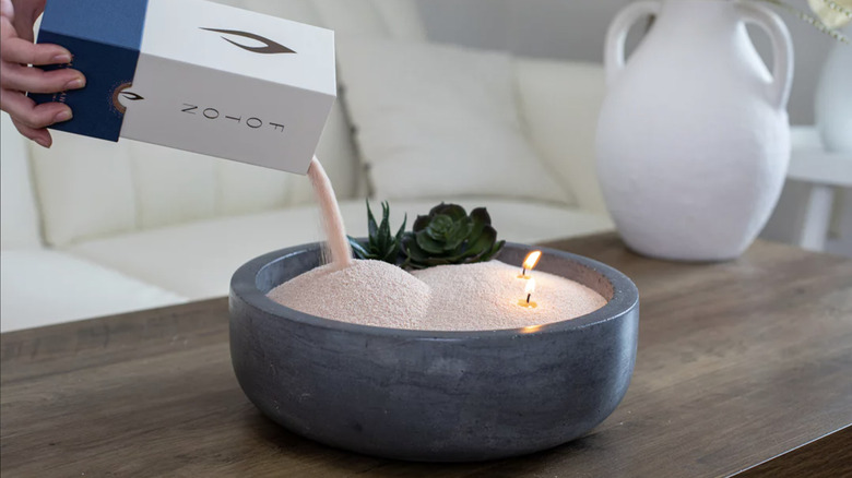 Woman refilling Foton candle with wax pearls on coffee table