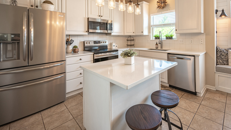 Beautifully designed kitchen with center bar, tile floor, French door fridge, stove and microwave