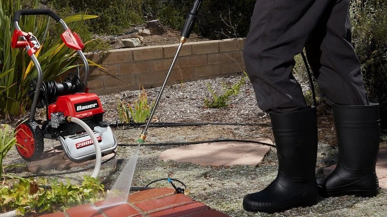 A person power washing a brick patio