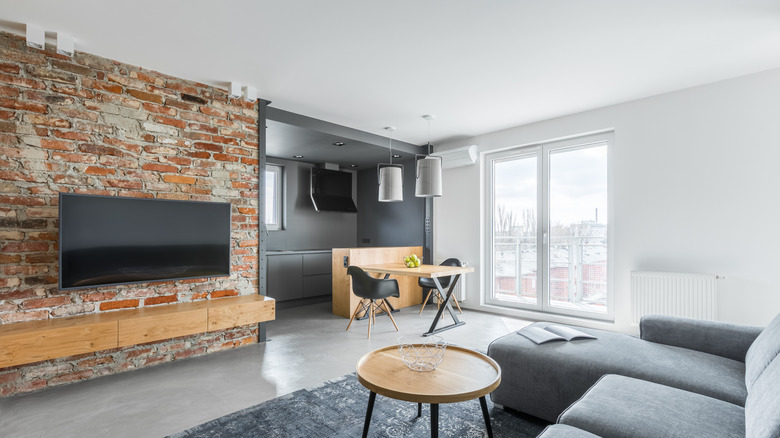 An industrial style living room with concrete floors and a brick wall