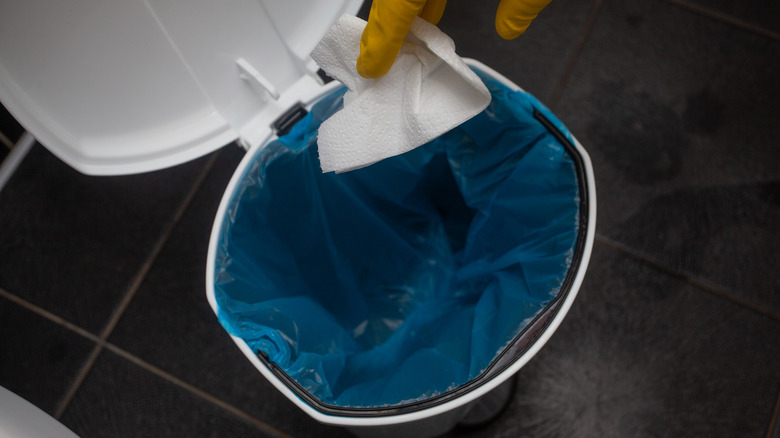person throwing napkin in trash can
