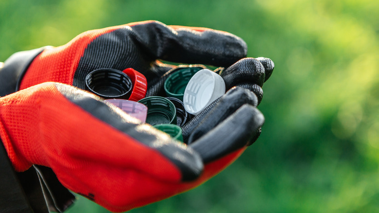 person with gardening gloves holding plastic bottle caps