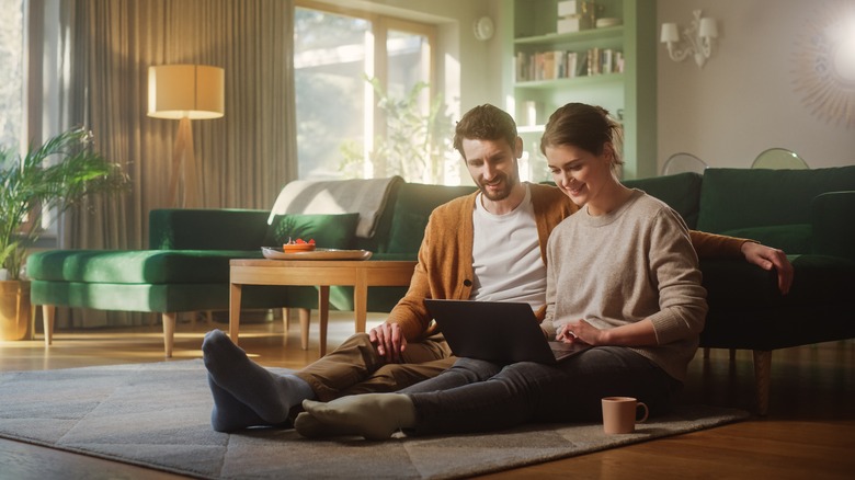 Couple sits and browses laptop