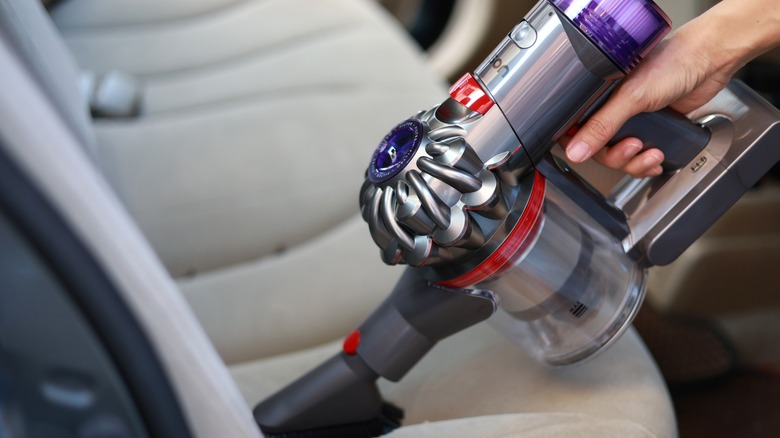 A close-up of a person using a Dyson vacuum