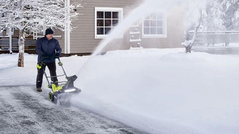 A man using the Ryobi 40V cordless electric snow blower to clear his yard