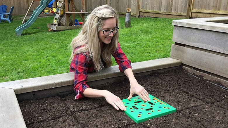 A women using the Seeding Square to set up her raised garden bed.